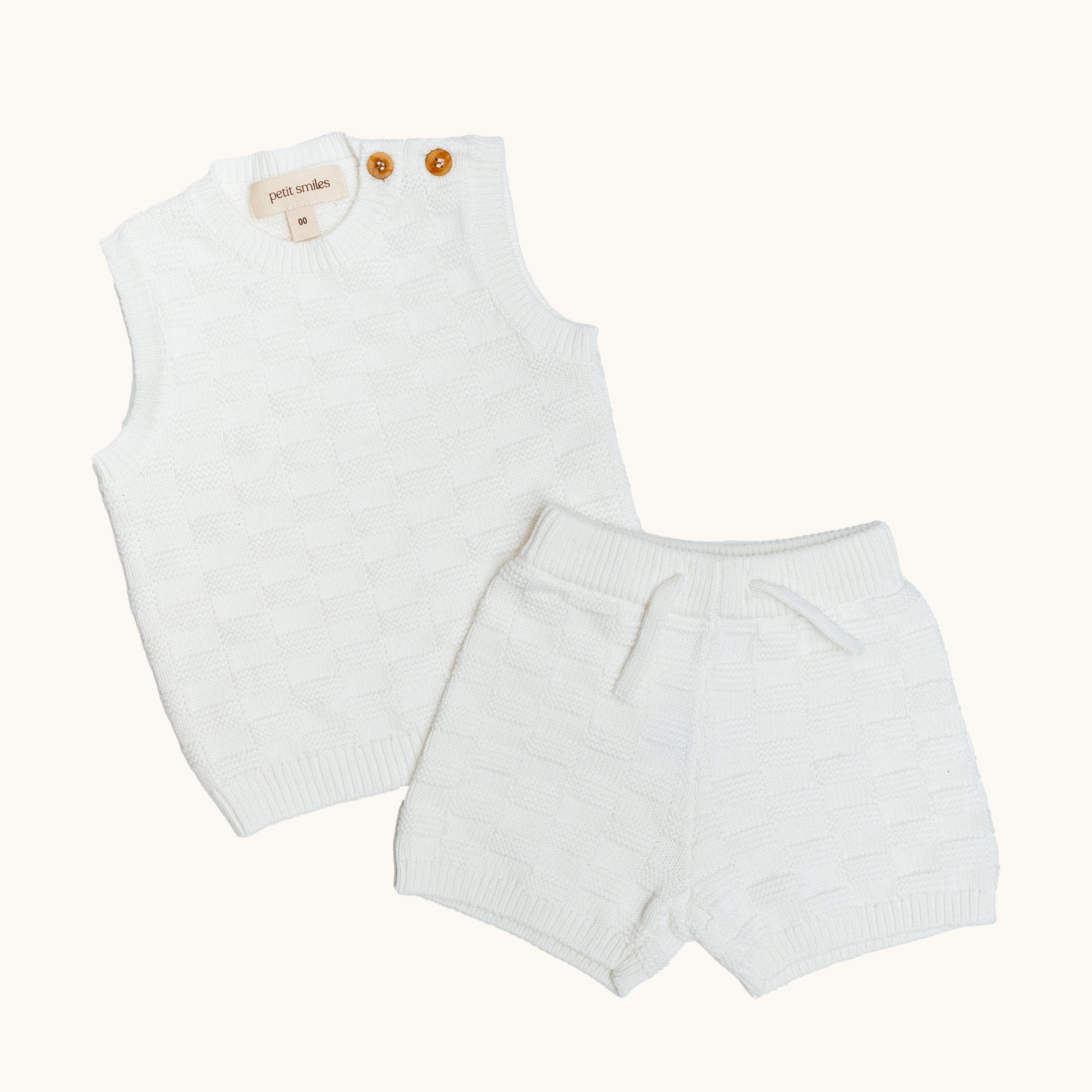 KNITTED BUTTONED WAISTCOAT - CREAM; 100% Organic Cotton; Waistcoat made from GOTS-certified organic cotton; Wooden button at shoulder for easy dressing; Rib finish at neck, hem and cuffs; Relaxed fit.